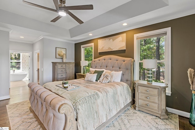 bedroom featuring a tray ceiling, ceiling fan, ornamental molding, and wood-type flooring