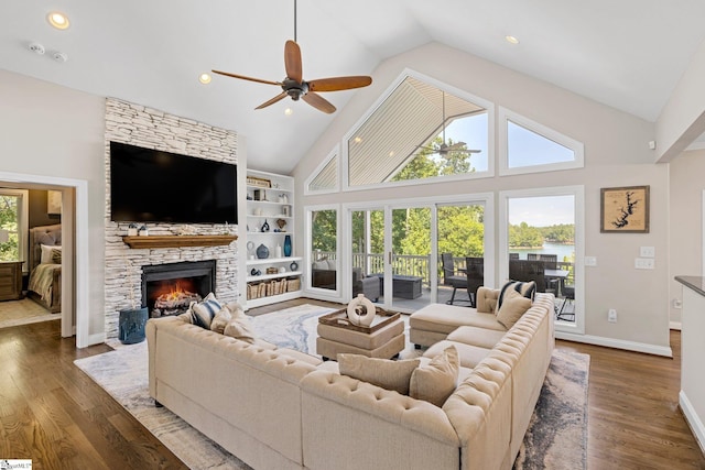 living room featuring built in shelves, a fireplace, high vaulted ceiling, ceiling fan, and hardwood / wood-style flooring