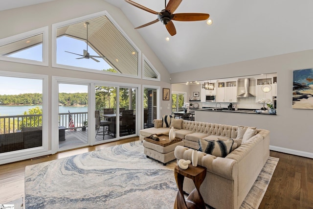 living room with ceiling fan, high vaulted ceiling, wood-type flooring, and a water view