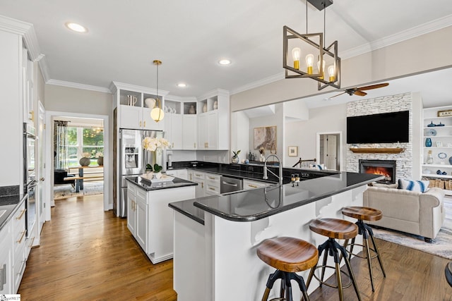 kitchen featuring a fireplace, ceiling fan with notable chandelier, white cabinetry, and wood-type flooring