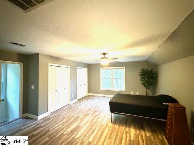 bedroom with hardwood / wood-style flooring, ceiling fan, lofted ceiling, and a textured ceiling