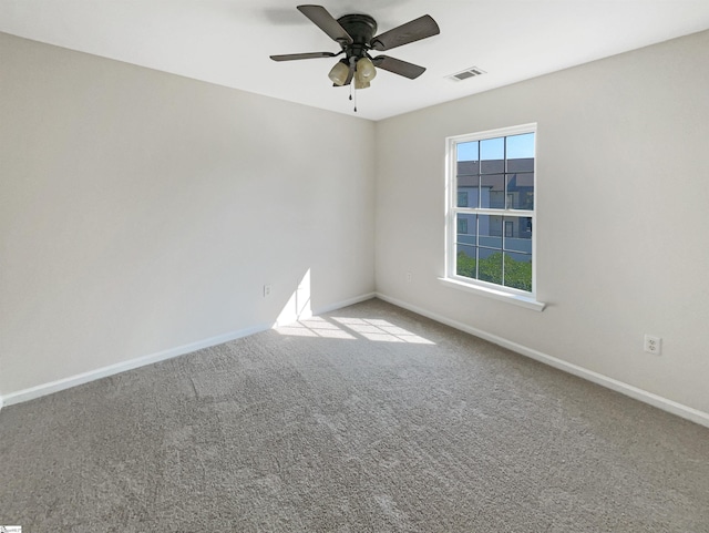 carpeted spare room featuring baseboards, visible vents, and a ceiling fan