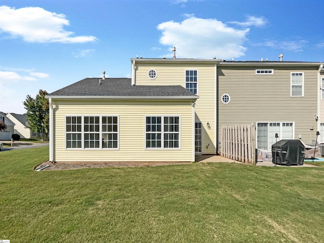 back of property with roof with shingles and a lawn