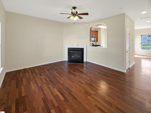 unfurnished living room with dark wood-type flooring, a fireplace with flush hearth, visible vents, and baseboards