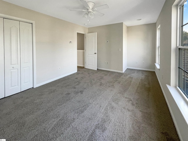 unfurnished bedroom featuring a ceiling fan, carpet, a closet, and baseboards