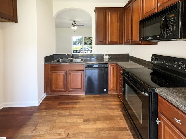 kitchen featuring wood finished floors, a sink, a ceiling fan, baseboards, and black appliances