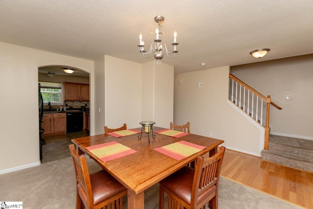 dining space with sink, a notable chandelier, a textured ceiling, and light carpet