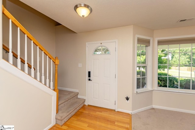 entryway with a wealth of natural light, light hardwood / wood-style flooring, and a textured ceiling