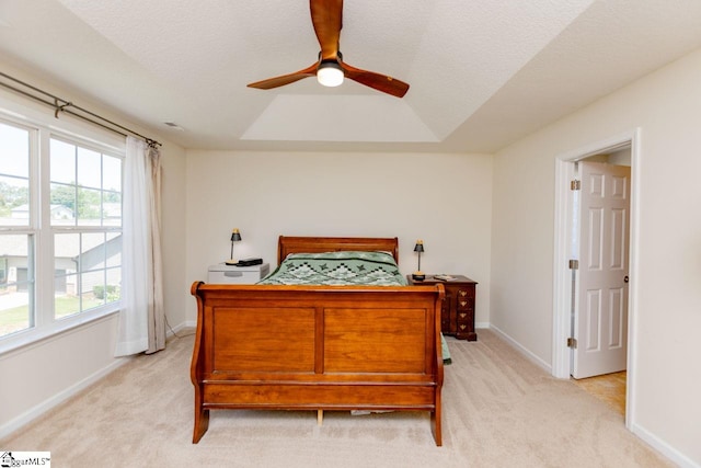 carpeted bedroom with a textured ceiling, ceiling fan, and a raised ceiling