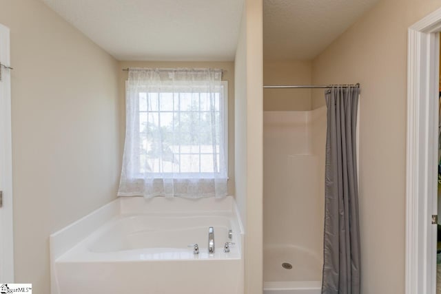 bathroom with a textured ceiling and shower with separate bathtub