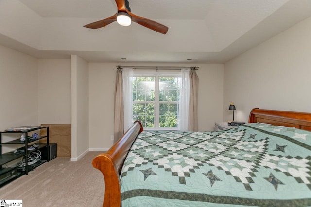 carpeted bedroom featuring ceiling fan and a tray ceiling