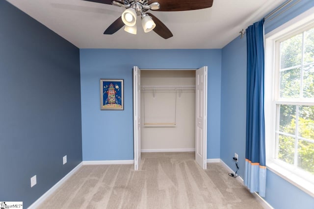 unfurnished bedroom featuring ceiling fan, a closet, light carpet, and multiple windows