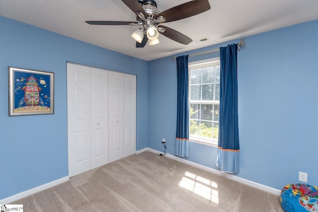 unfurnished bedroom featuring ceiling fan, carpet, and a closet