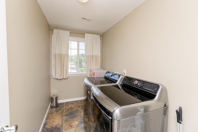 laundry area with washing machine and dryer and dark tile patterned floors