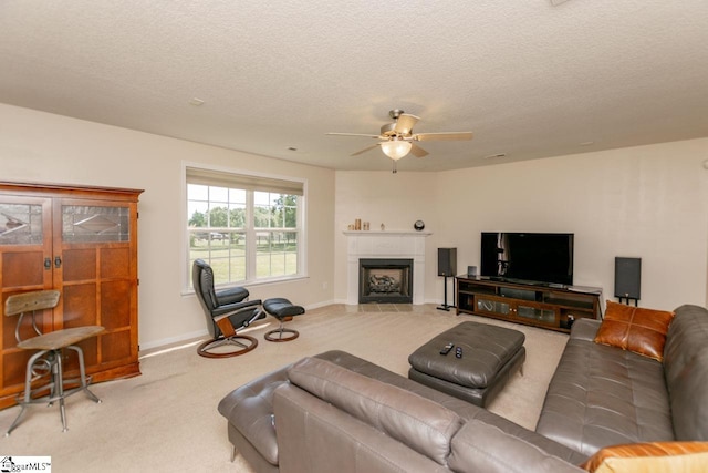 carpeted living room featuring ceiling fan, a textured ceiling, and a tiled fireplace