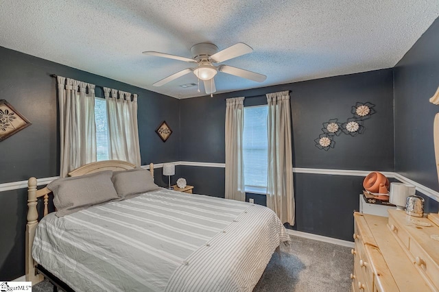 bedroom with ceiling fan, dark carpet, and a textured ceiling