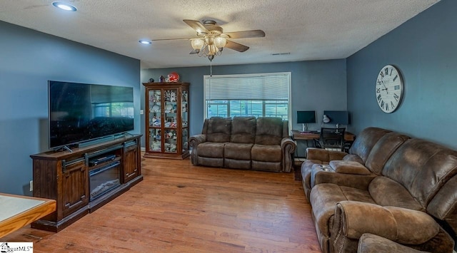 living room featuring hardwood / wood-style flooring, a textured ceiling, and ceiling fan