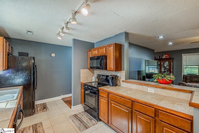 kitchen with tasteful backsplash, a textured ceiling, black appliances, and light tile patterned flooring