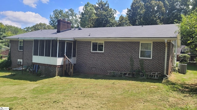 rear view of house featuring central AC unit, a yard, and a sunroom