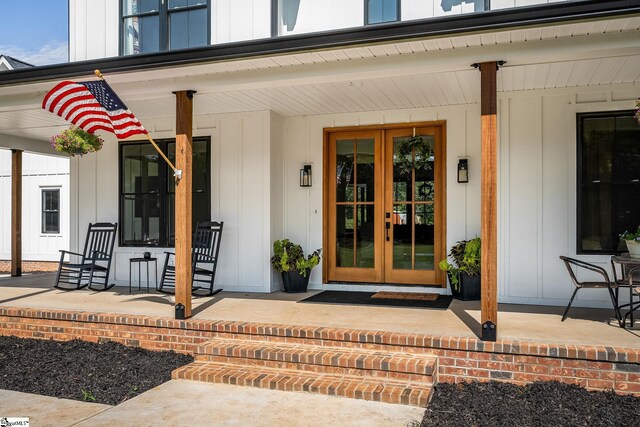 view of exterior entry with french doors and a porch