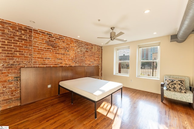 dining room with dark wood-type flooring, brick wall, and ceiling fan