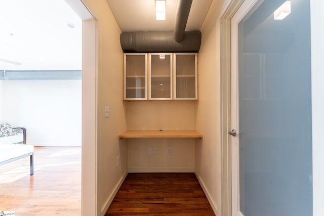 hallway with dark wood-style flooring and baseboards