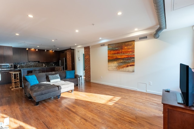 living room featuring brick wall and light hardwood / wood-style flooring