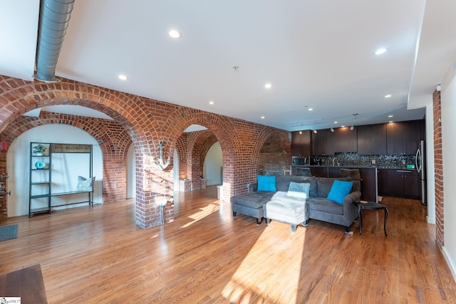 living room featuring light wood-type flooring and brick wall