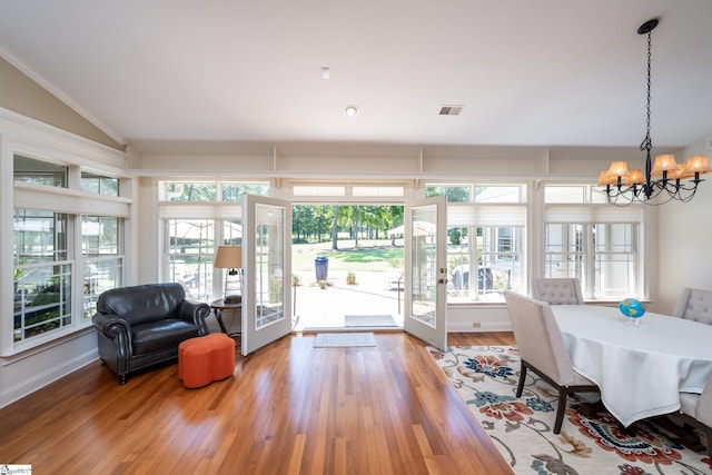 interior space with a chandelier, french doors, wood finished floors, and a healthy amount of sunlight