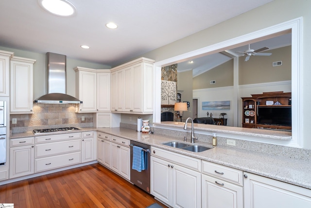 kitchen with stainless steel appliances, lofted ceiling, visible vents, a sink, and wall chimney range hood