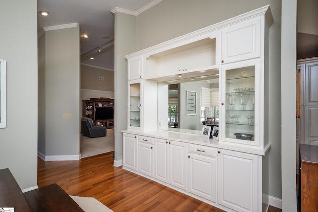 bar with dark wood-style flooring, crown molding, and baseboards