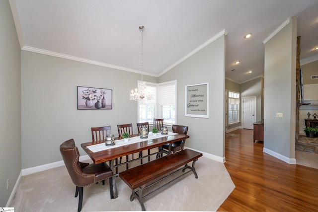 dining space featuring baseboards, ornamental molding, vaulted ceiling, and wood finished floors