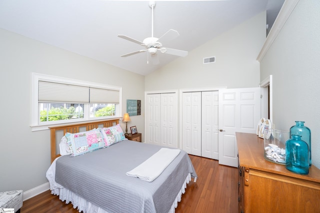 bedroom featuring a ceiling fan, visible vents, dark wood finished floors, and multiple closets