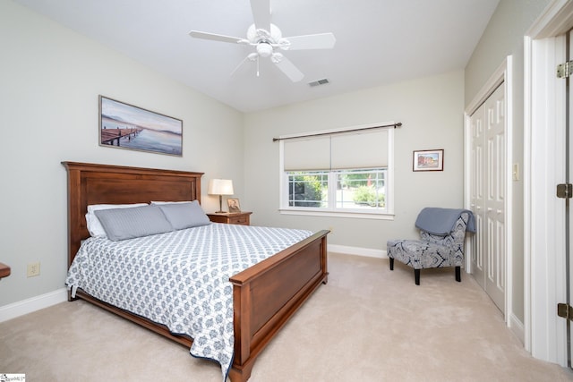 bedroom with a closet, light colored carpet, visible vents, ceiling fan, and baseboards