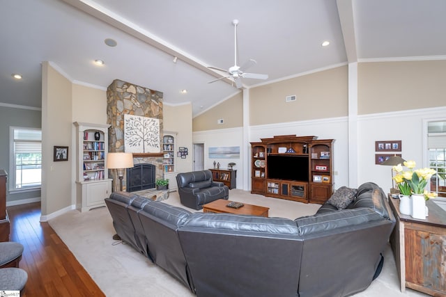 living area featuring vaulted ceiling, ornamental molding, a fireplace, and wood finished floors