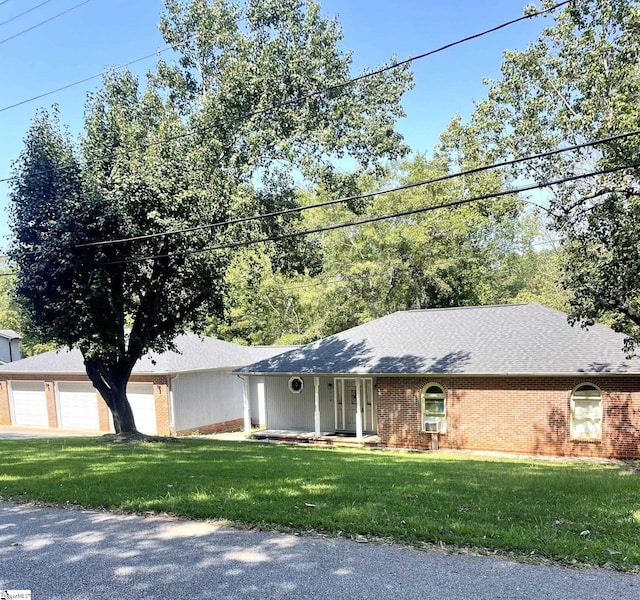 single story home with covered porch, a garage, and a front lawn