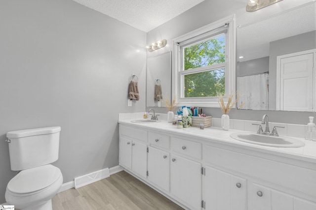 full bathroom with toilet, wood finished floors, a sink, and visible vents