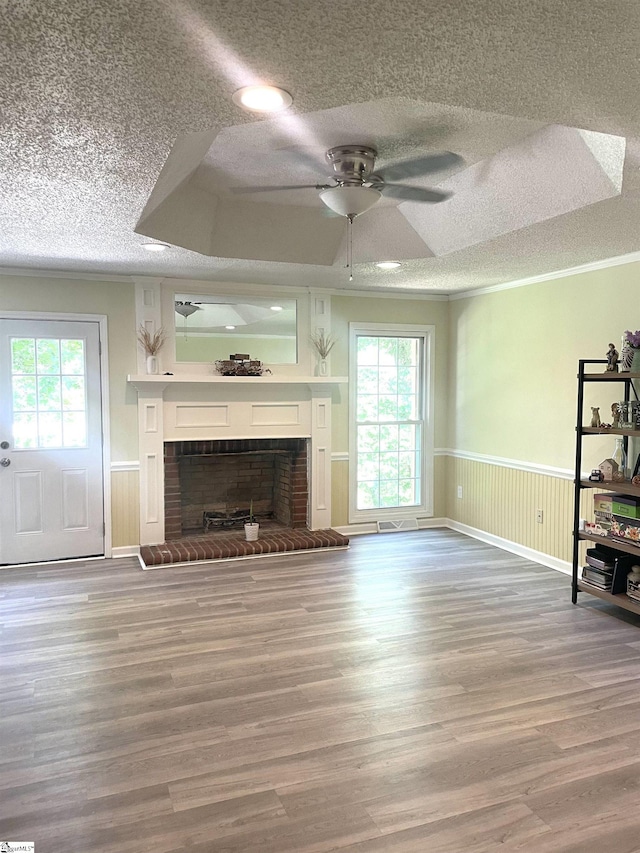 unfurnished living room featuring plenty of natural light, ceiling fan, wood-type flooring, and a fireplace