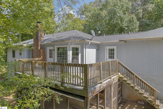 rear view of house with roof with shingles, a chimney, and a wooden deck