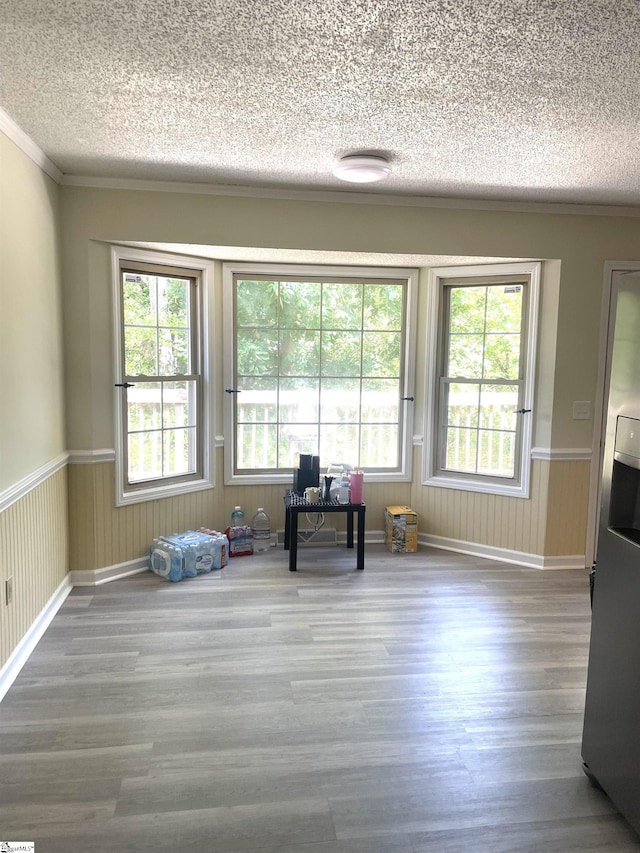 unfurnished room featuring crown molding, a textured ceiling, and hardwood / wood-style flooring