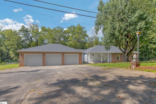 ranch-style home featuring driveway, brick siding, and an attached garage