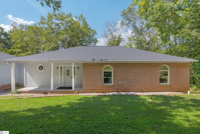 ranch-style house featuring covered porch, roof with shingles, a front yard, and brick siding