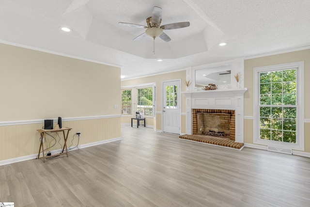 unfurnished living room with crown molding, wood finished floors, a textured ceiling, and wainscoting