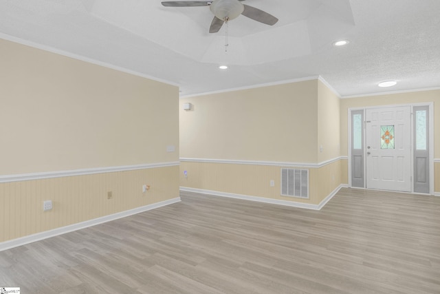 foyer entrance featuring light wood finished floors, wainscoting, and visible vents