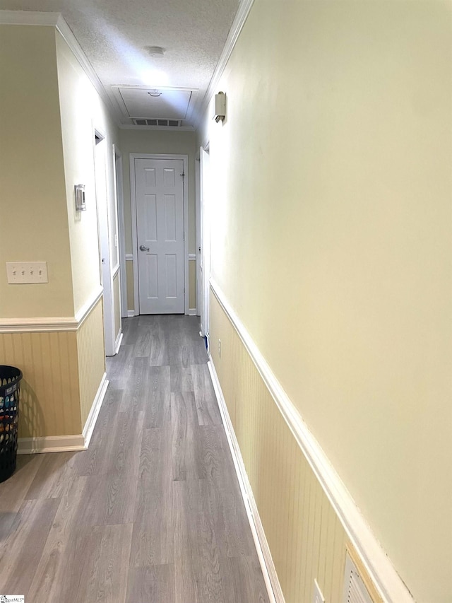 hall with crown molding, a textured ceiling, wood-type flooring, and wood walls