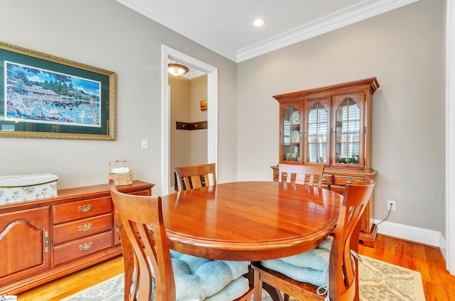 dining room with crown molding and light hardwood / wood-style flooring