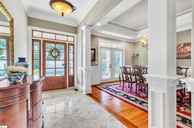 tiled entryway featuring a tray ceiling, decorative columns, crown molding, and french doors