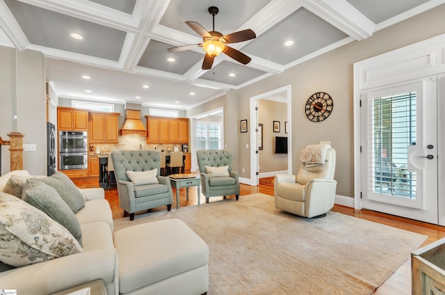 living room featuring coffered ceiling, crown molding, ceiling fan, beam ceiling, and light hardwood / wood-style floors