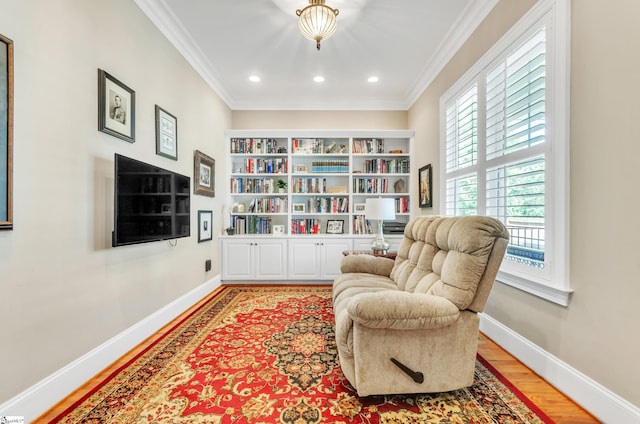 sitting room with ornamental molding and light hardwood / wood-style flooring