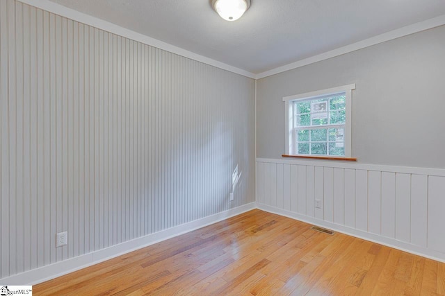 spare room featuring ornamental molding and light wood-type flooring